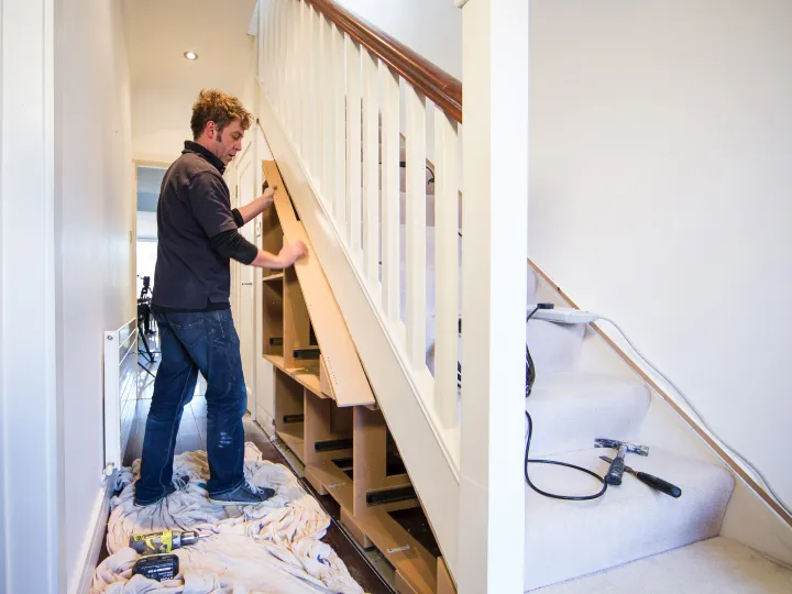 Bespoke under stairs storage cupboard installer in London measuring a staircase