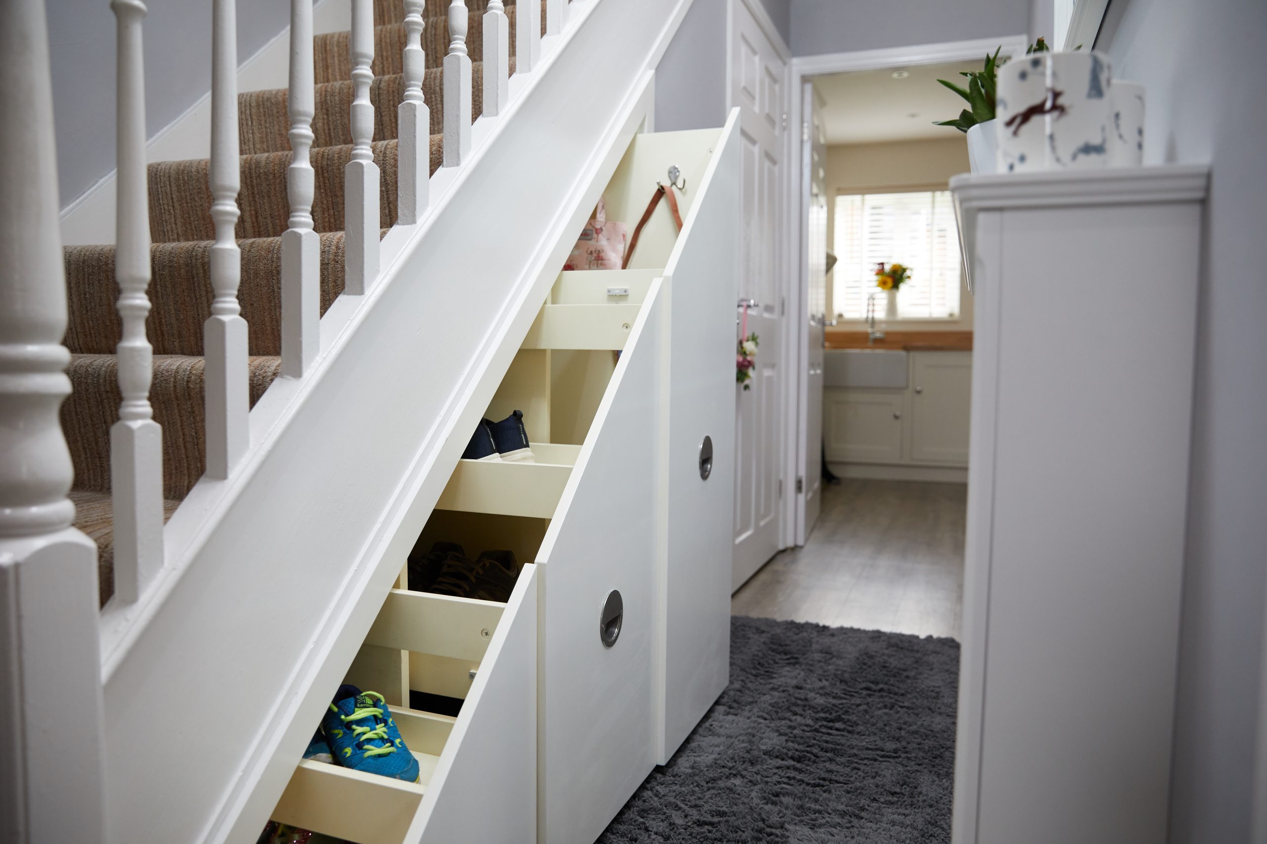 Understairs storage cupboard installer fitting custom wood panels in a London hallway